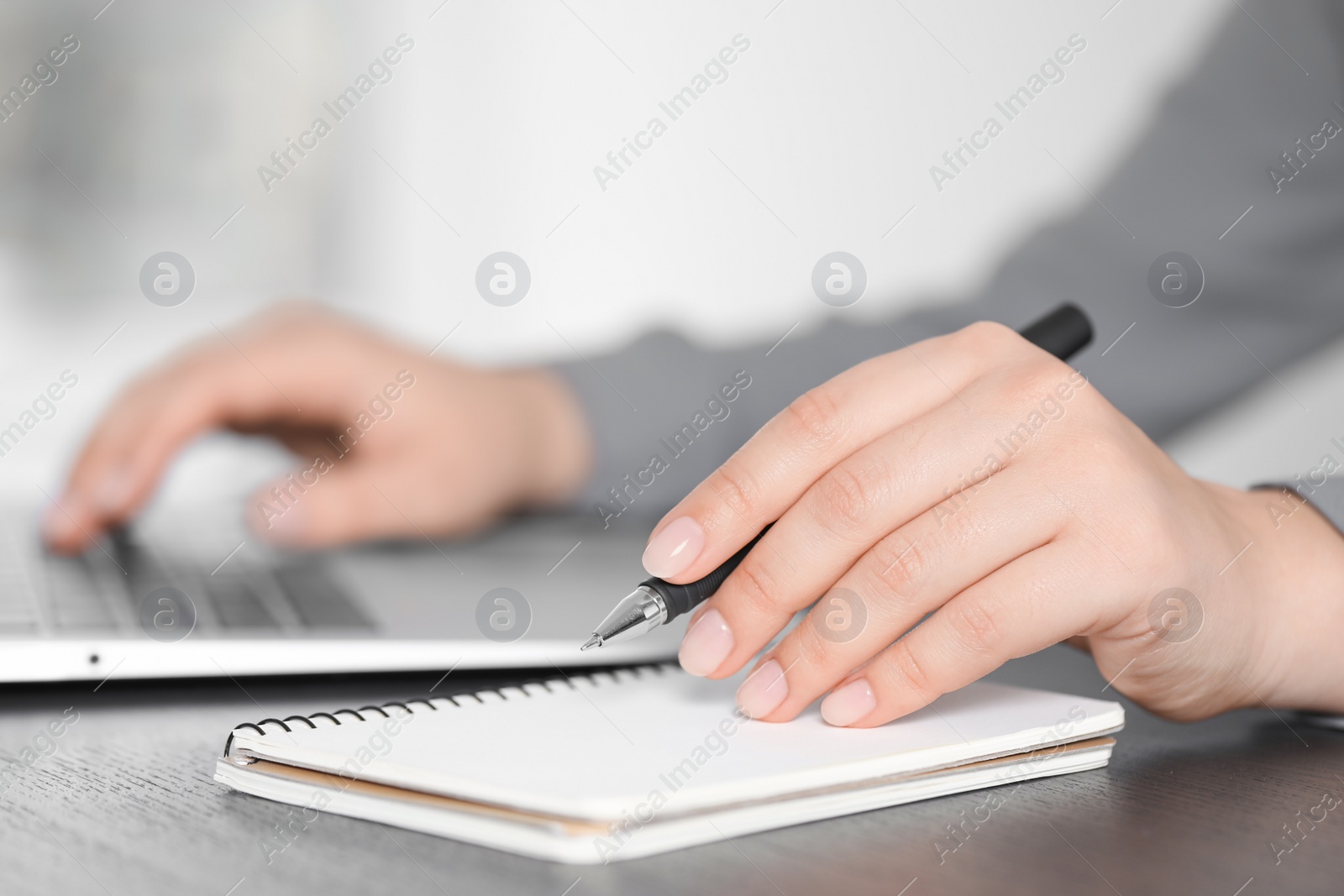 Photo of Woman with pen, laptop and notebook at wooden table, closeup. Electronic document management