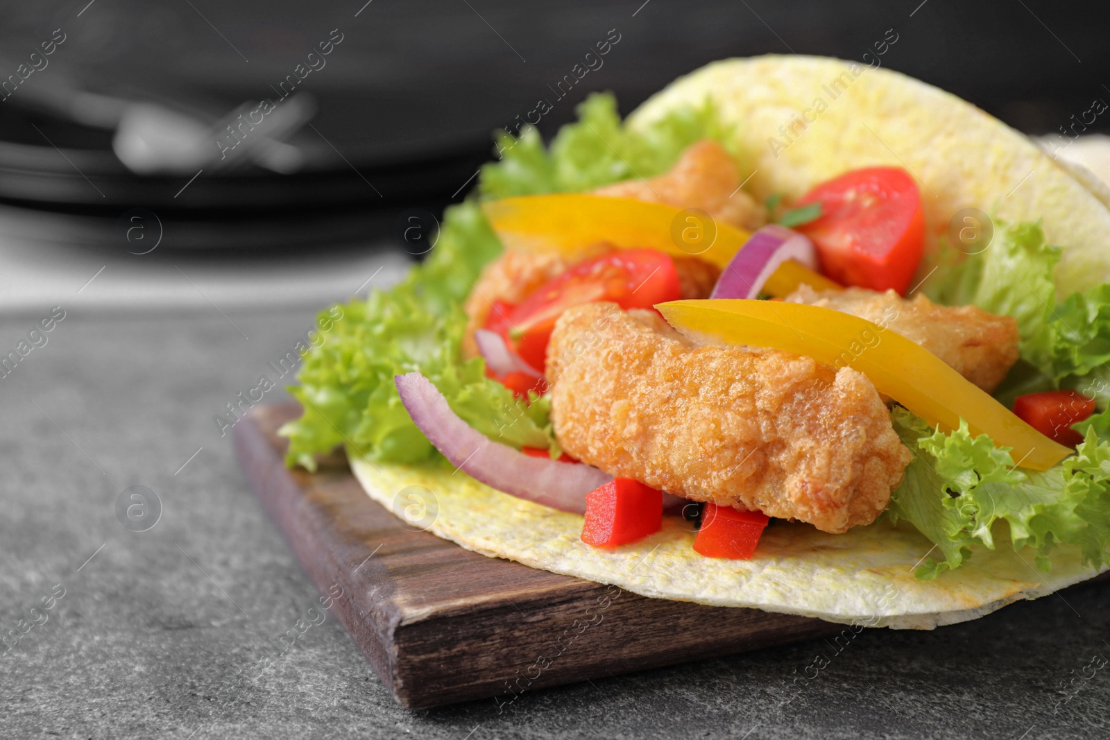 Photo of Delicious fish taco served on grey table, closeup