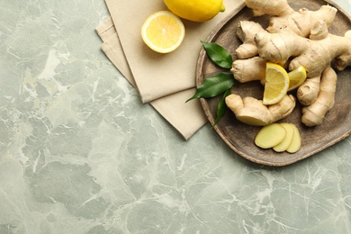 Photo of Fresh lemons and ginger on grey marble table, flat lay. Space for text