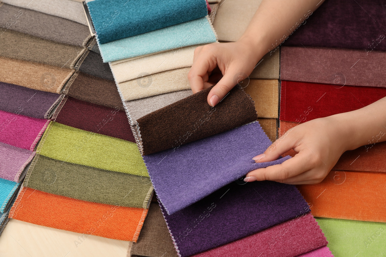 Photo of Woman choosing fabric among multicolored samples, closeup