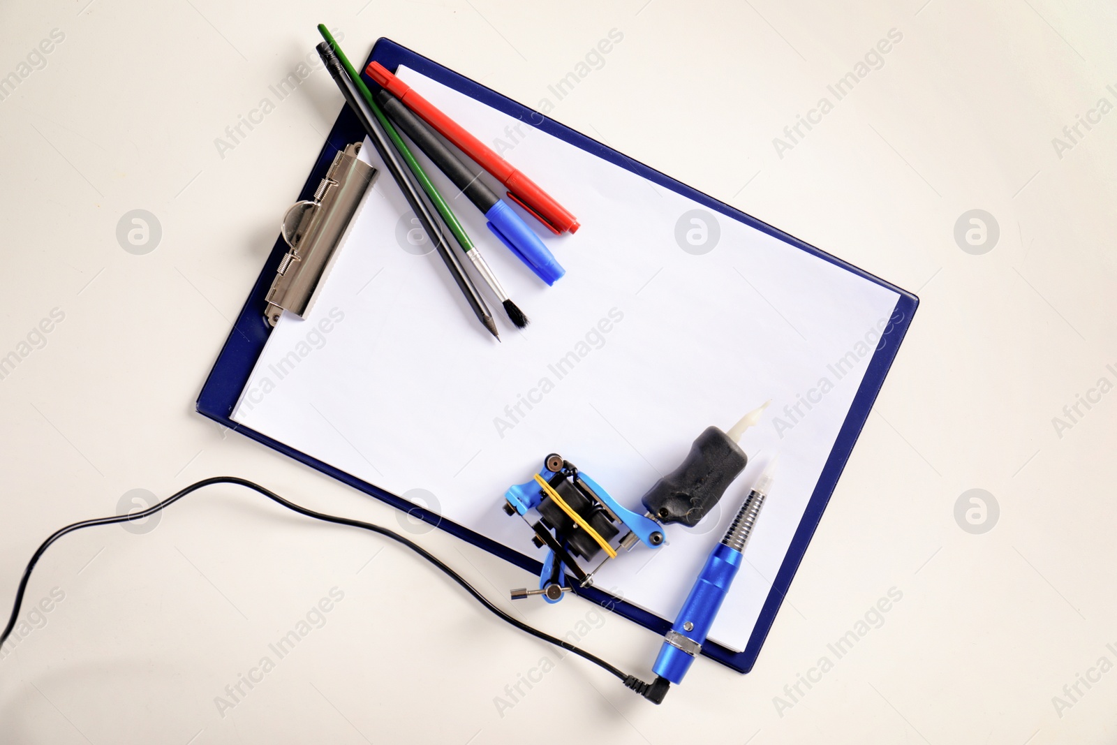 Photo of Composition with empty sheet of paper and tattoo machine on white background, top view. Space for text