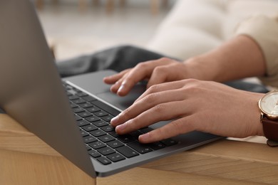 Photo of Man working on laptop at wooden table indoors, closeup