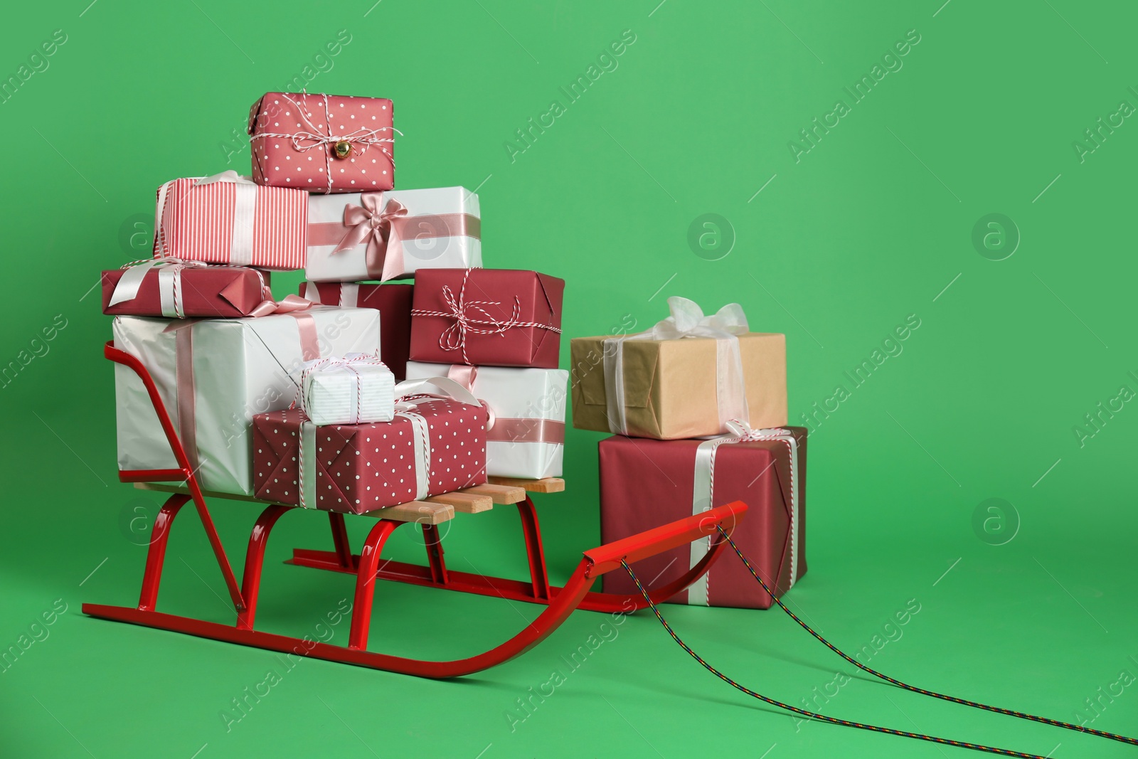 Photo of Sleigh and gift boxes on green background. Space for text