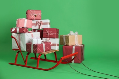 Sleigh and gift boxes on green background. Space for text