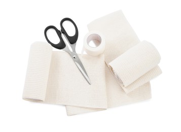 Photo of Medical bandage rolls, sticking plaster and scissors on white background, above view