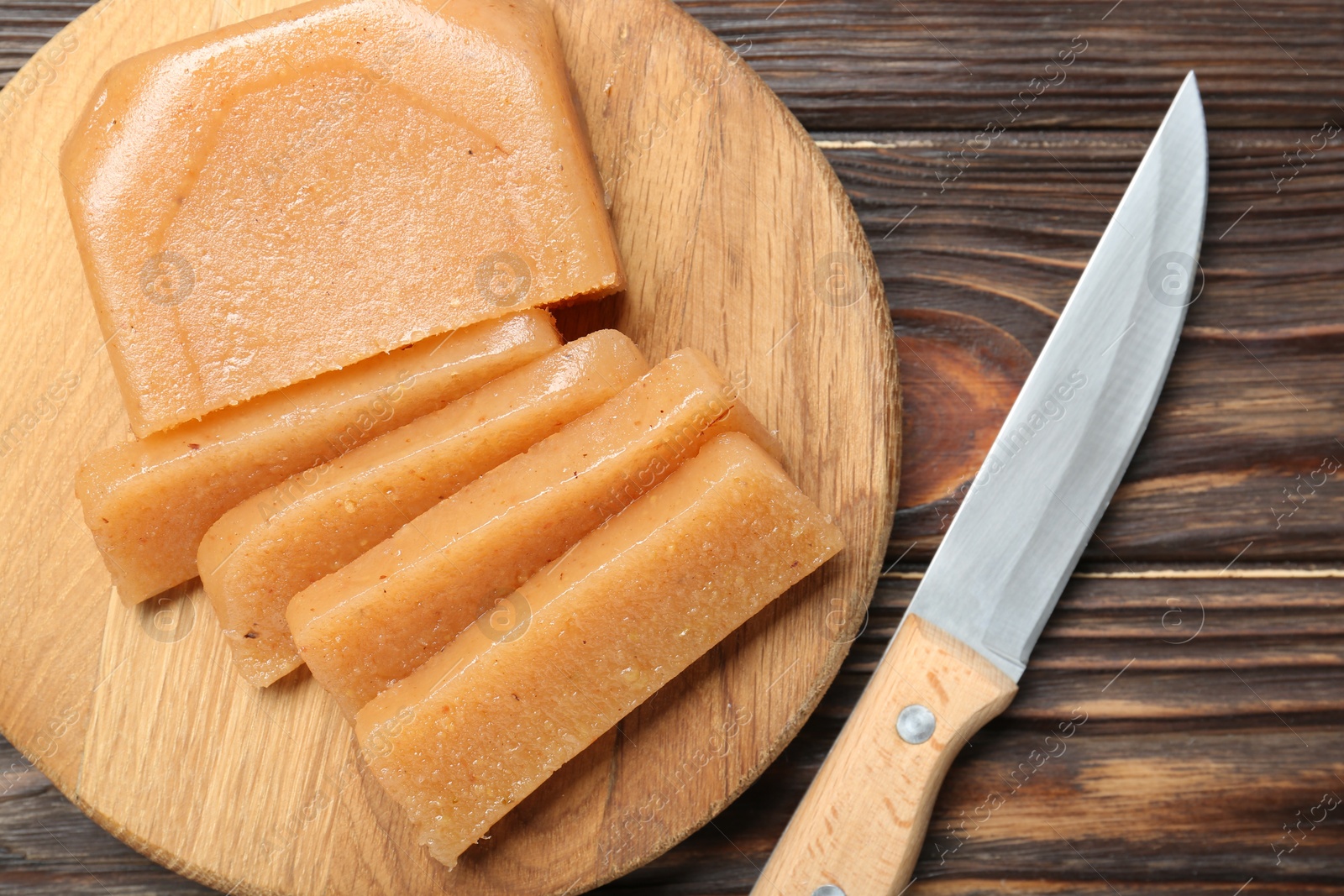 Photo of Tasty sweet quince paste and knife on wooden table, top view