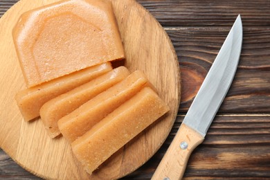 Tasty sweet quince paste and knife on wooden table, top view