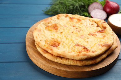 Photo of Delicious khachapuri with cheese on blue wooden table, closeup