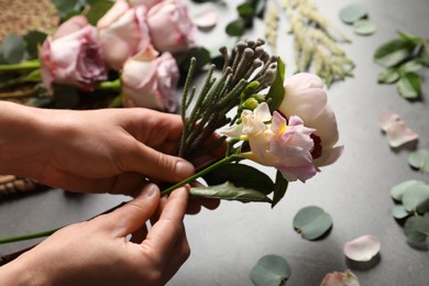 Photo of Florist creating beautiful bouquet at black table, closeup