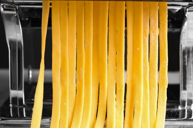 Photo of Pasta maker machine with raw dough , closeup