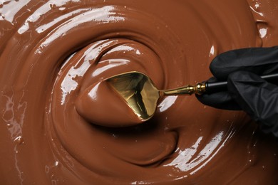 Person making tasty milk chocolate paste, top view