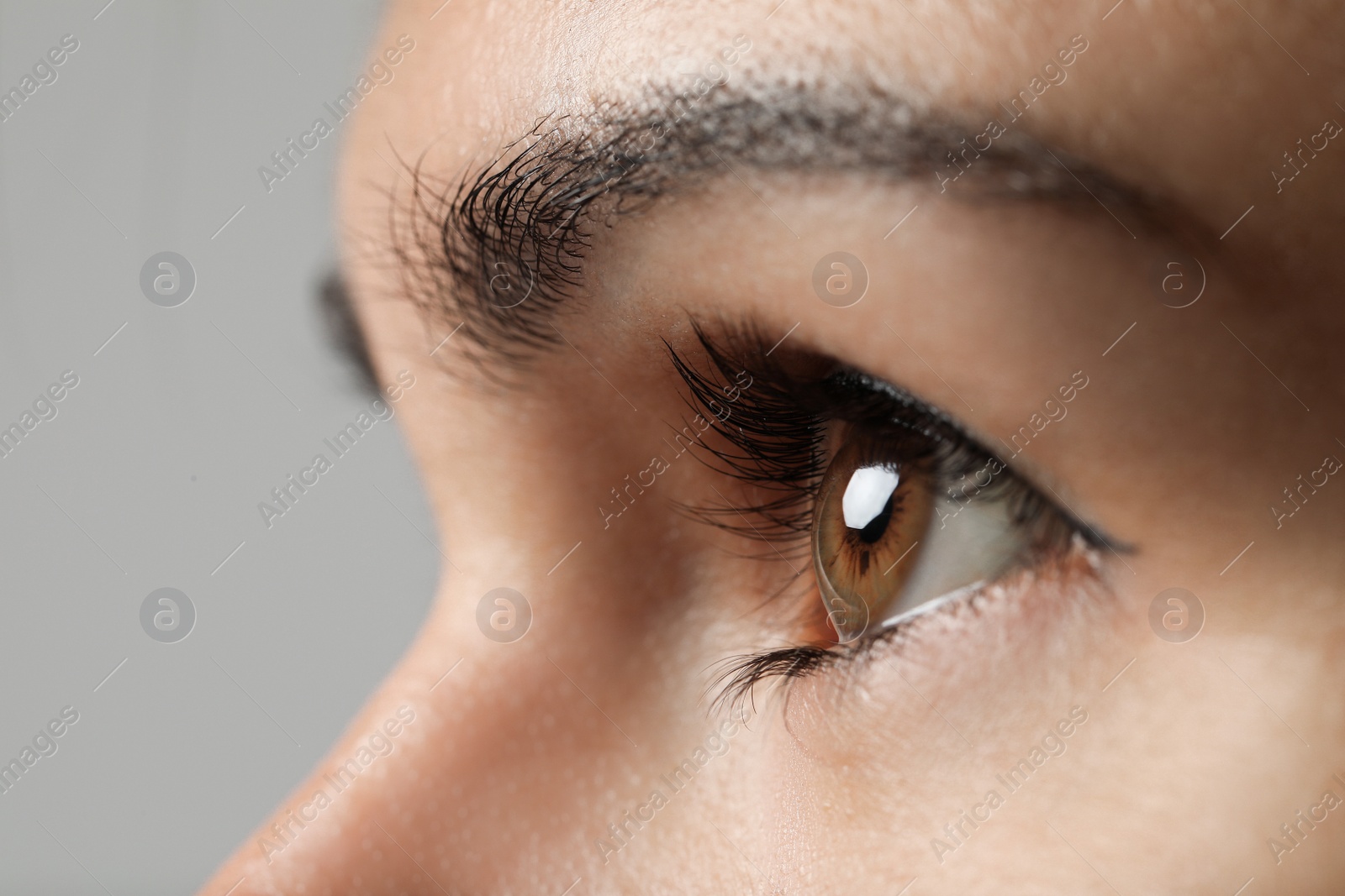 Photo of Beautiful woman with hazel eye on grey background, closeup