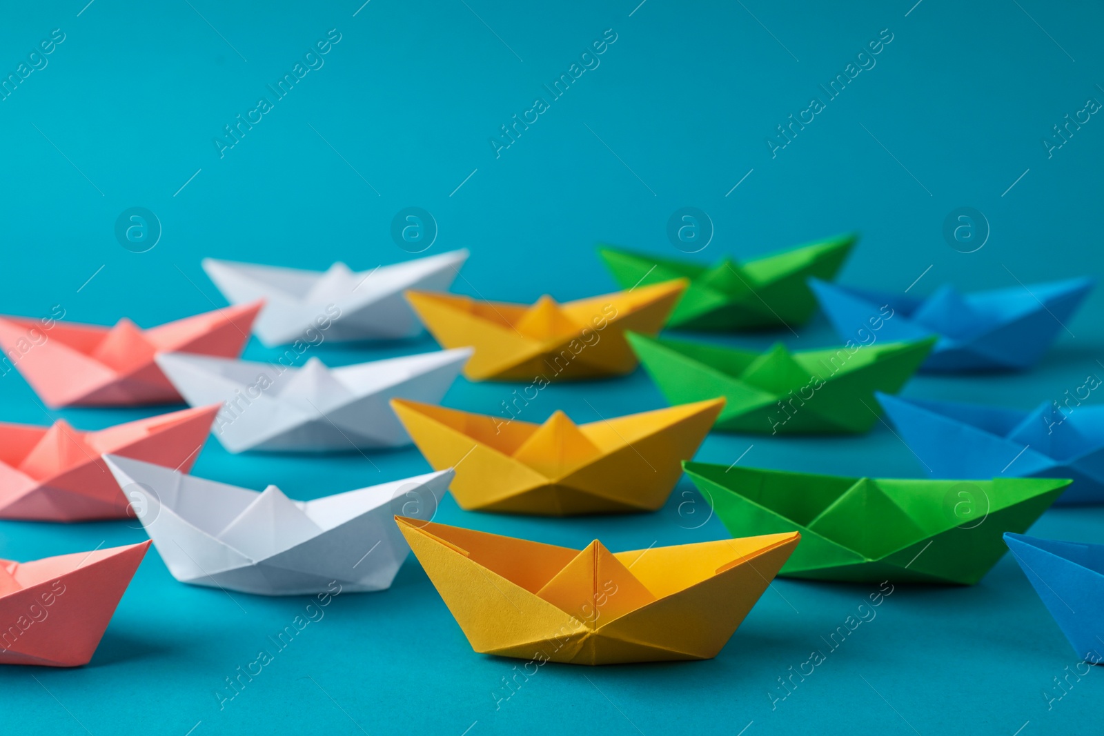 Photo of Many colorful handmade paper boats on light blue background. Origami art