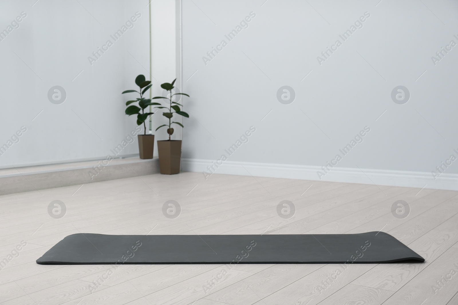 Photo of Unrolled black yoga mat on floor in room