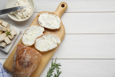 Photo of Slices of baguette with tofu cream cheese and rosemary on white wooden table, flat lay. Space for text