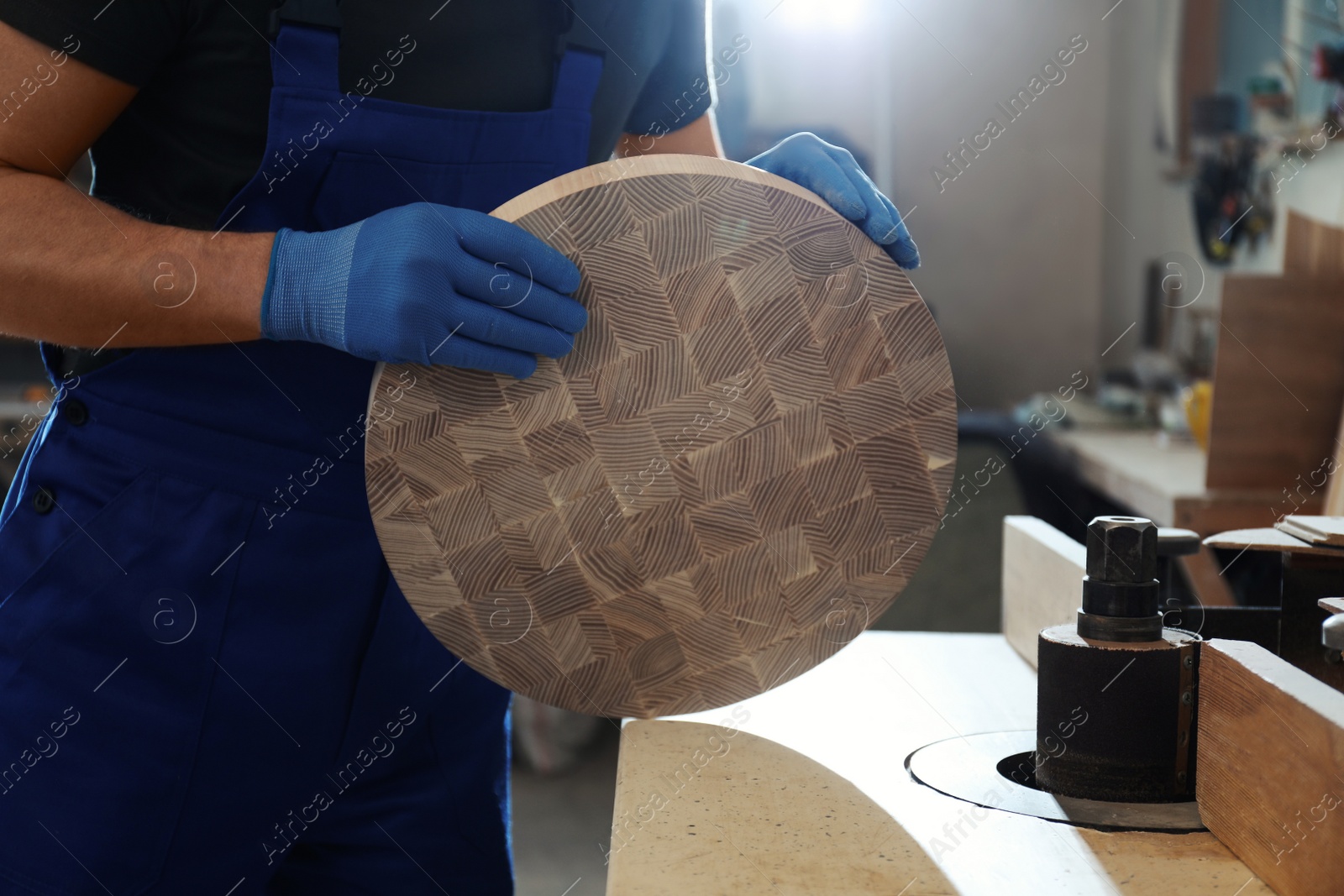 Photo of Professional carpenter grinding piece of wood in workshop, closeup