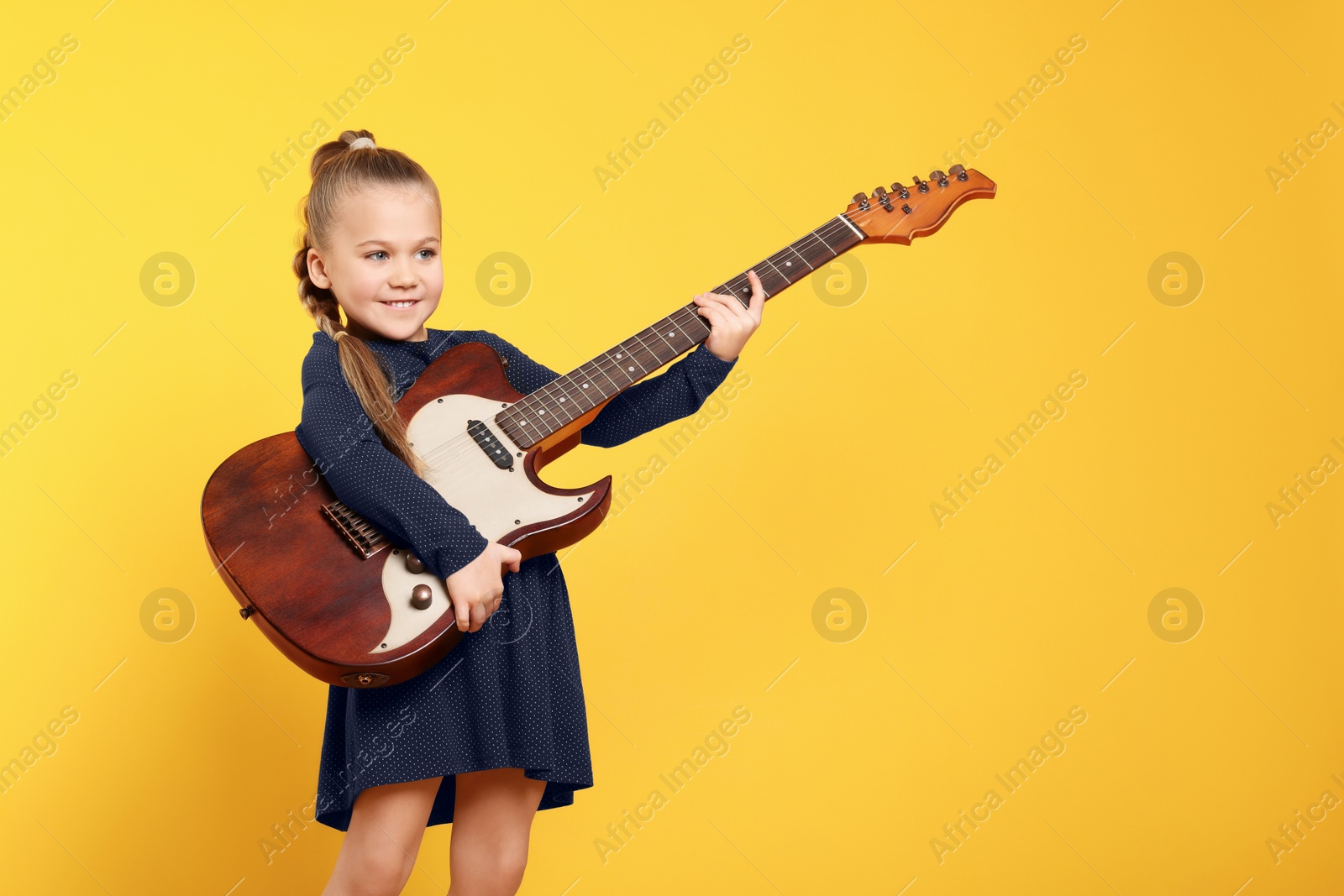 Photo of Happy girl with electric guitar on yellow background. Space for text