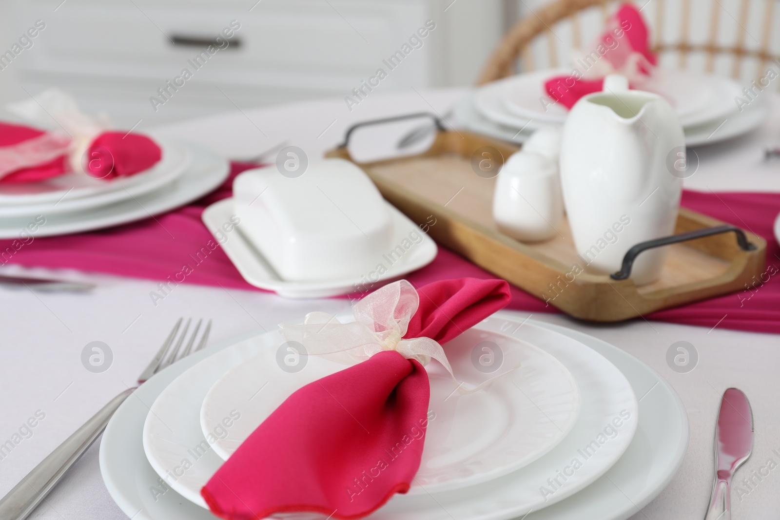 Photo of Color accent table setting. Plates, cutlery and pink napkin, closeup