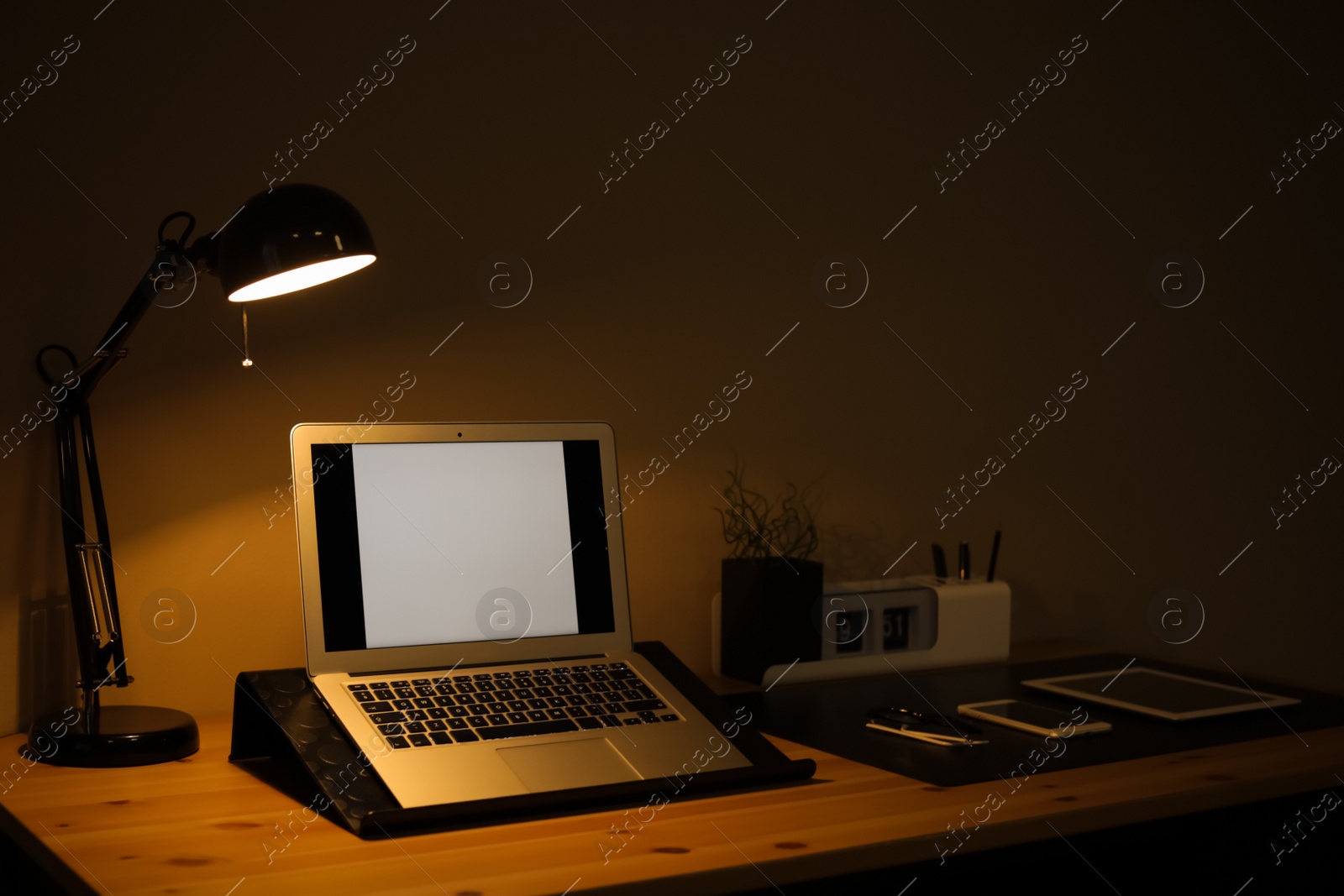 Photo of Dark room interior with laptop and devices on table. Space for text