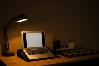 Dark room interior with laptop and devices on table. Space for text