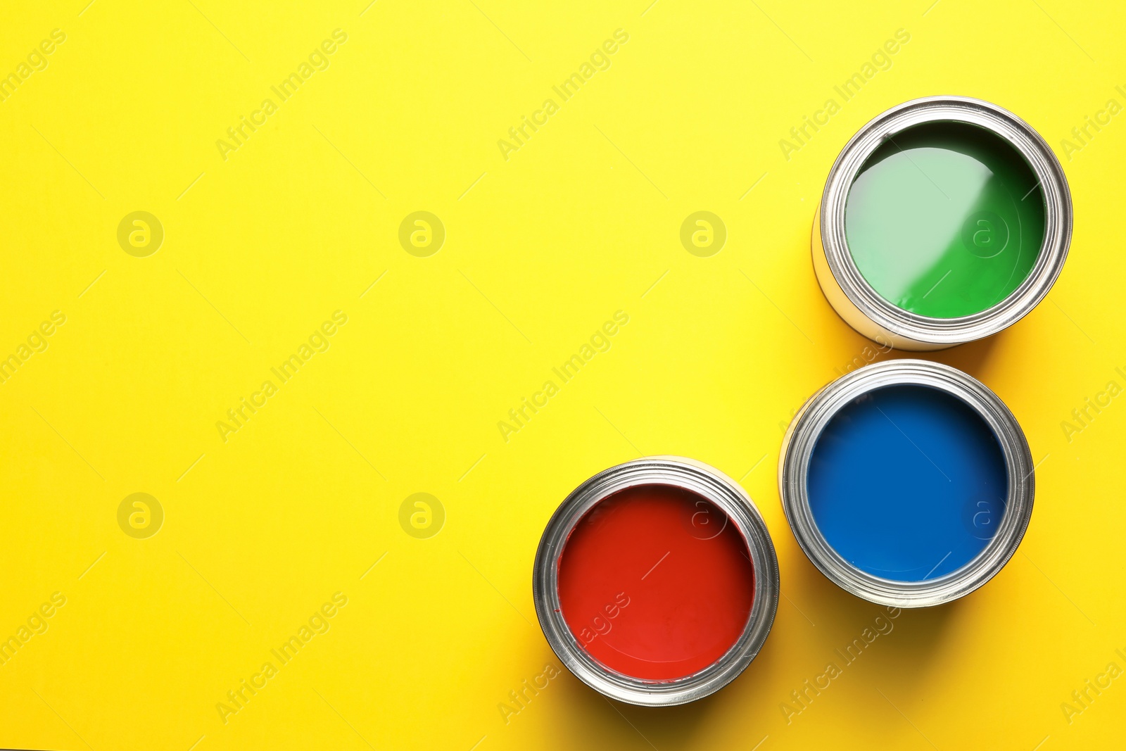 Photo of Open paint cans and space for text on color background, top view