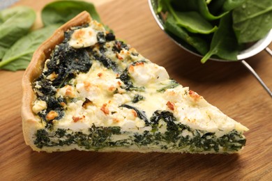 Photo of Piece of delicious homemade spinach quiche in wooden table, closeup