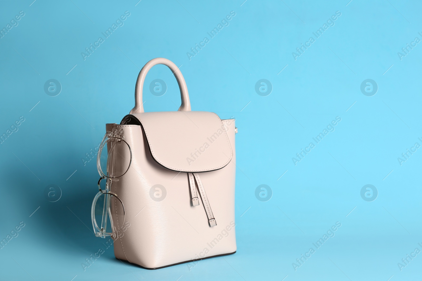 Photo of Stylish woman's bag on light blue background. Space for text