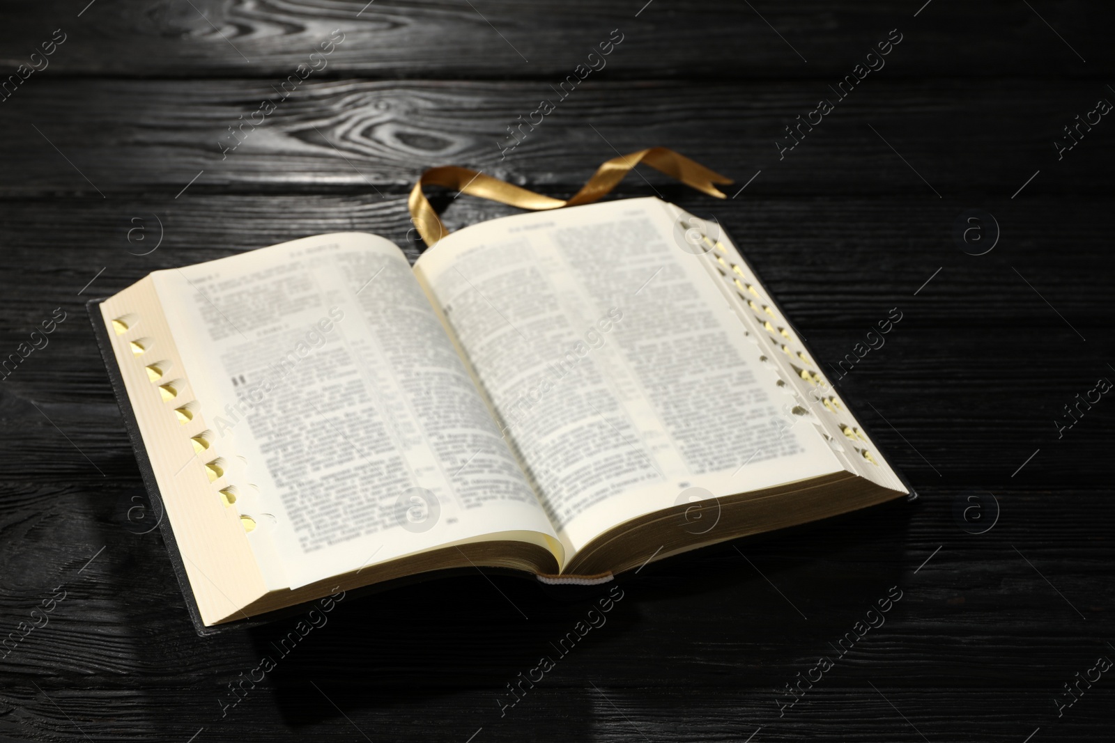 Photo of Open Bible on black wooden table. Christian religious book