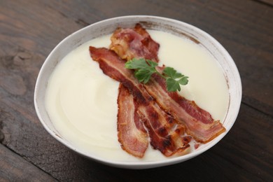 Photo of Delicious potato soup with bacon and parsley on wooden table