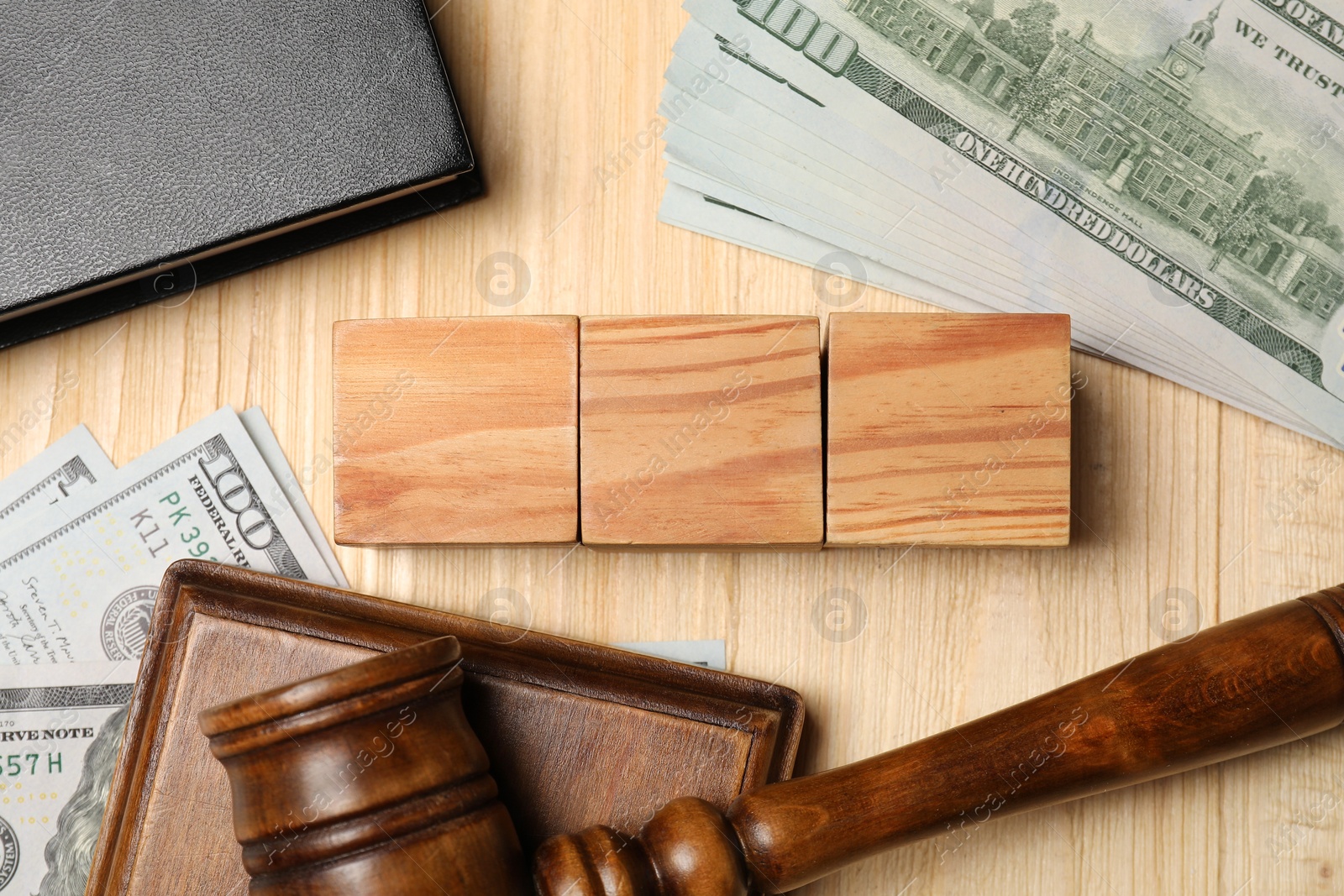 Photo of Tax law. Blank cubes, gavel, dollar banknotes and notebook on wooden table, flat lay