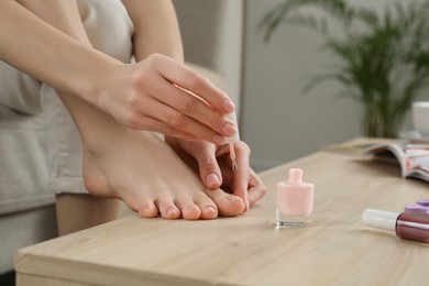 Woman giving herself pedicure at home, closeup