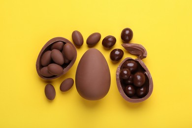 Photo of Delicious chocolate eggs and sweets on yellow background, flat lay
