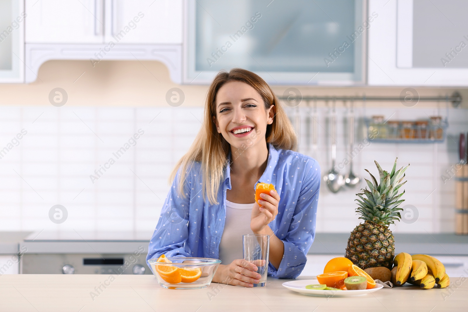 Photo of Woman making orange juice at table in kitchen. Healthy diet