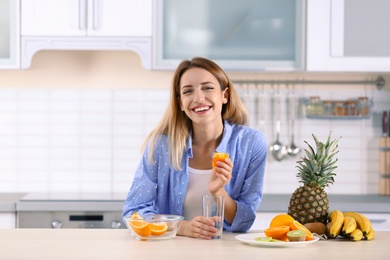 Photo of Woman making orange juice at table in kitchen. Healthy diet