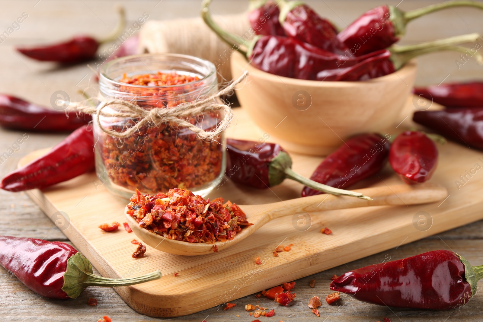 Photo of Chili pepper flakes and pods on wooden table