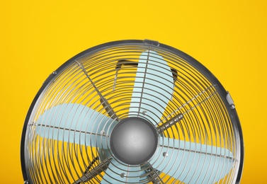 Photo of Modern electric fan on yellow background, closeup