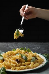 Photo of Woman eating delicious pasta with anchovies and basil at table, closeup