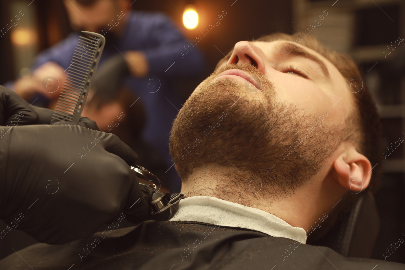 Photo of Professional hairdresser working with client in barbershop