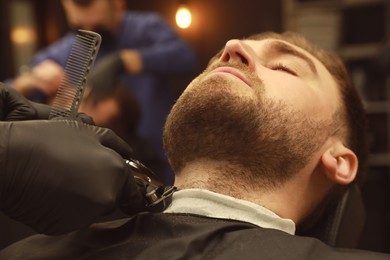 Professional hairdresser working with client in barbershop