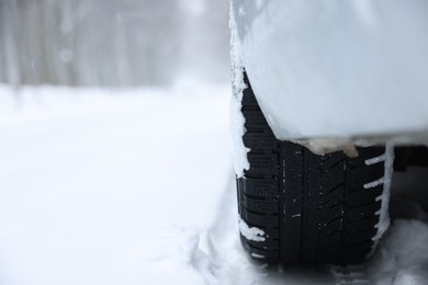 Photo of Car with winter tires on snowy road outdoors, closeup. Space for text
