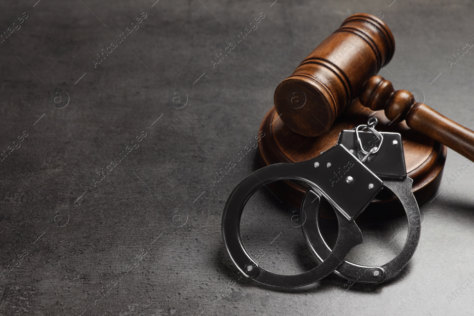 Photo of Judge's gavel and handcuffs on grey background, space for text. Criminal law concept