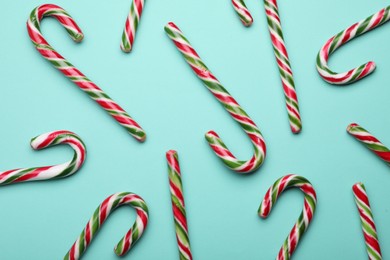 Photo of Many sweet Christmas candy canes on turquoise background, flat lay