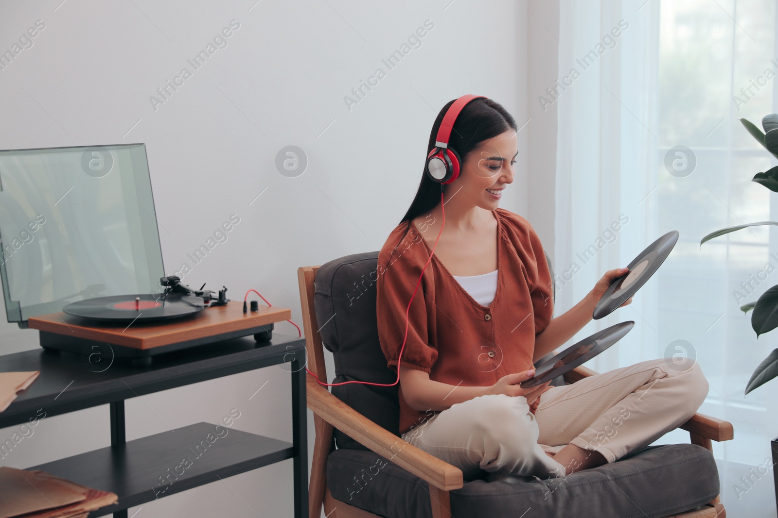 Photo of Woman listening to music with turntable at home