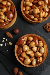 Photo of Tartlets with caramelized nuts on black table, top view. Delicious dessert