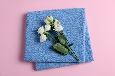 Photo of Soft folded blue towel with flowers on pink background, top view