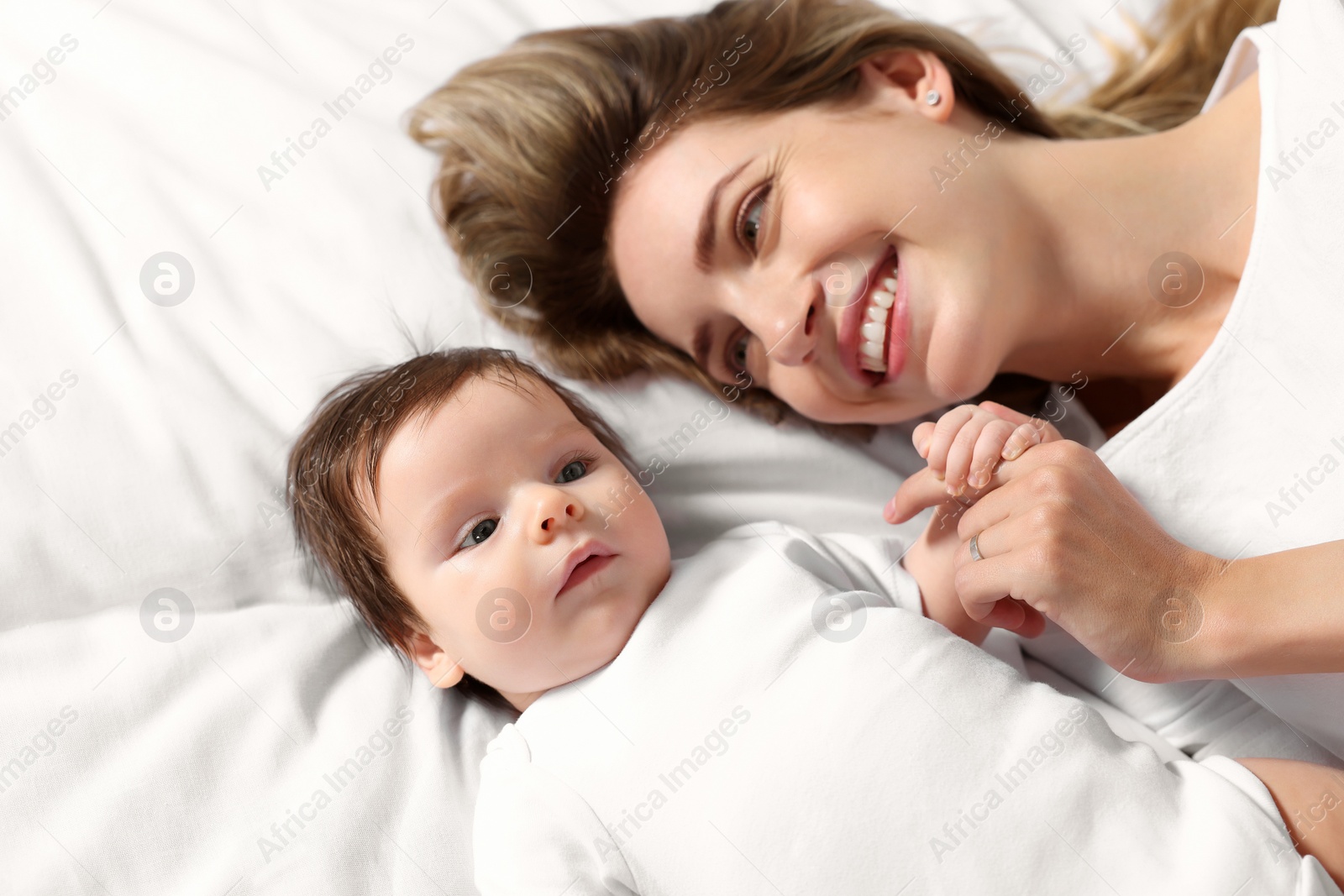 Photo of Mother and her little baby lying on bed