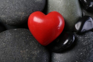 Photo of Red decorative heart on pebble stones, closeup