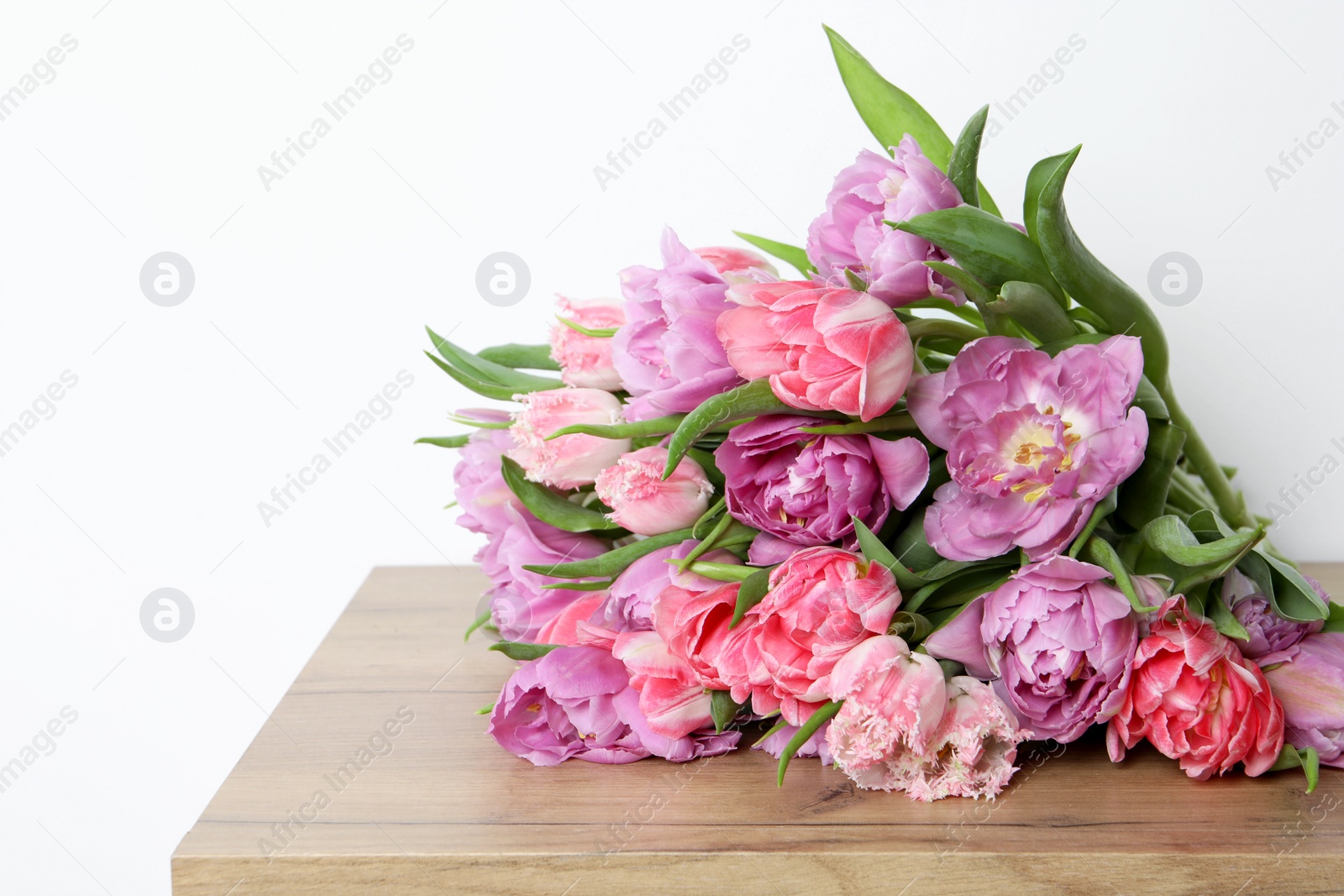 Photo of Beautiful bouquet of colorful tulip flowers on wooden table. Space for text