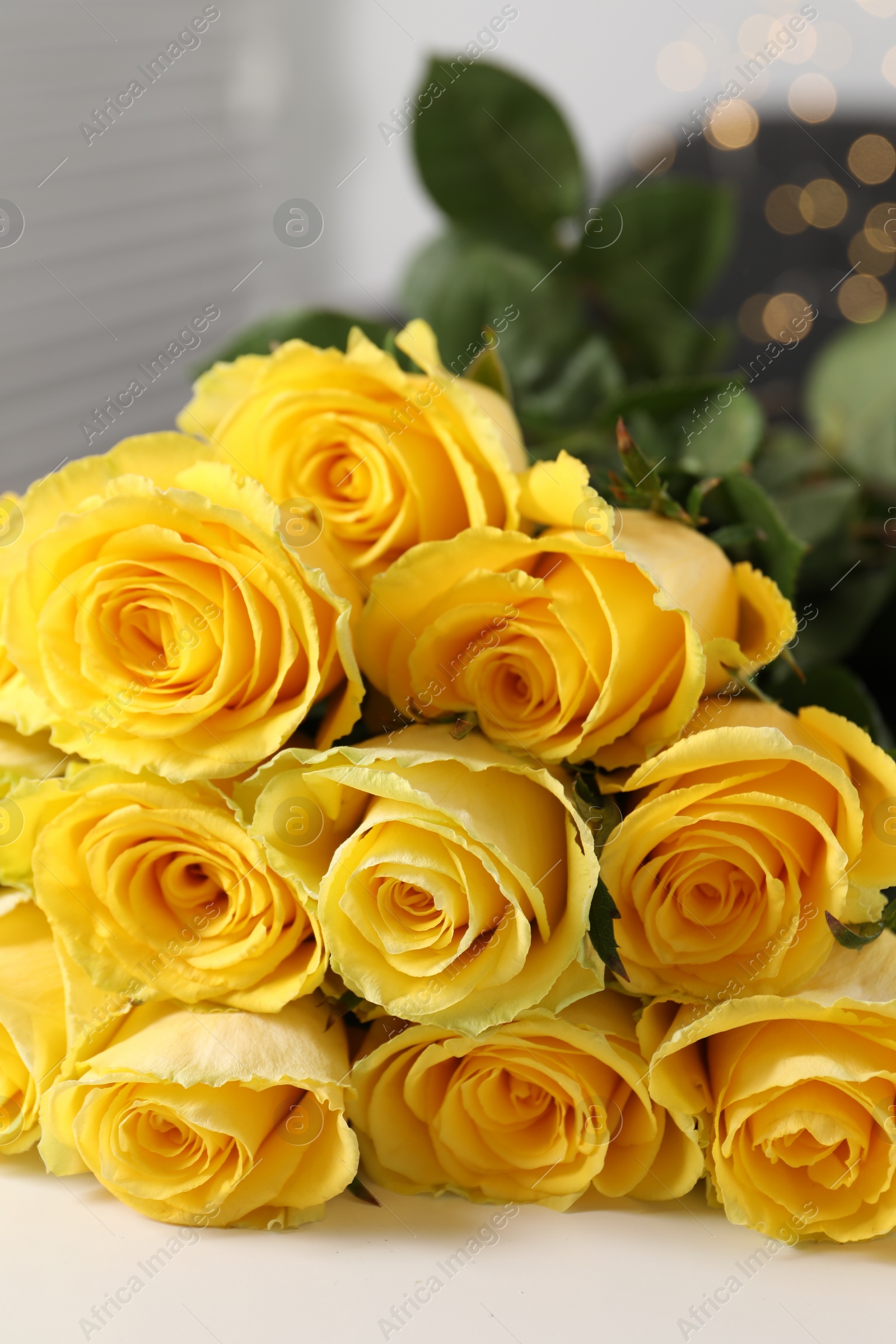 Photo of Beautiful bouquet of yellow roses on white table, closeup