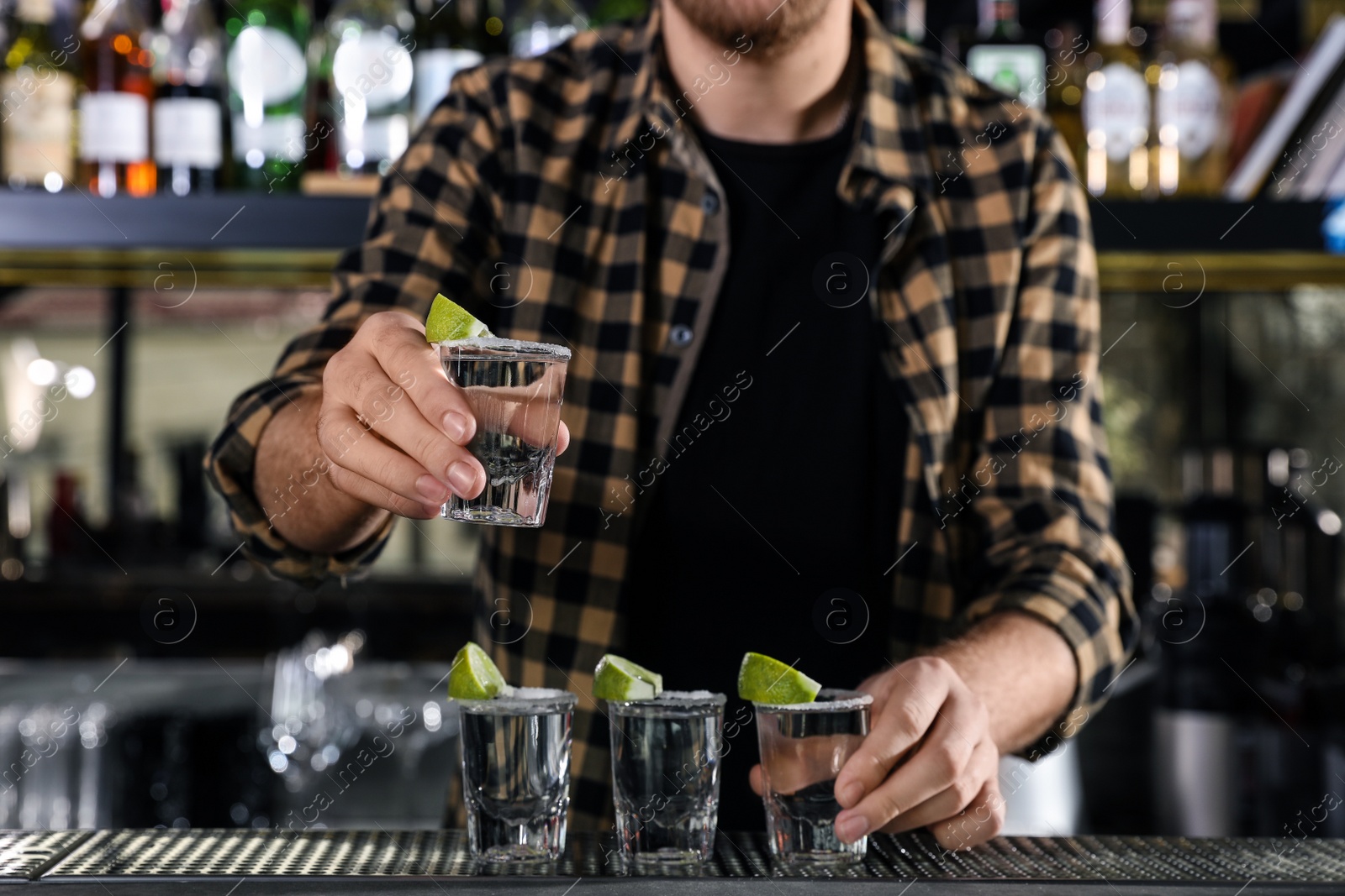 Photo of Bartender with shots of Mexican Tequila at bar counter, closeup